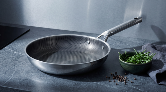 Hive Hybrid stainless-steel frying pan with its textured hybrid cooking surface on a dark slate worktop in cool daylight